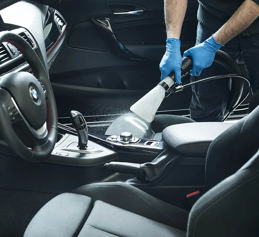 Aspiration de l'habitacle d'une voiture avec des gants de protection